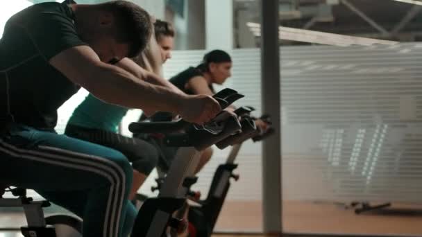 Спортсменка дорослі бікіні, двоє чоловіків і одна жінка симулятор їзди на велосипеді — стокове відео