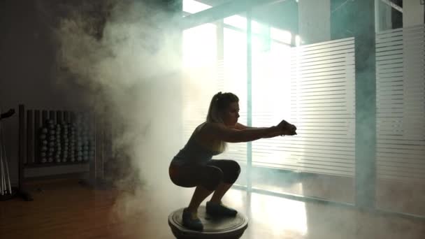 Красива сексуальна дівчина присідає на півкулі в спортзалі — стокове відео