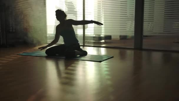 Silhuetten av en sportig tjej som gör yoga i gymmet på sportmatta — Stockvideo