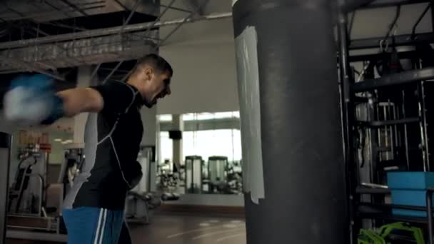 Imágenes en cámara lenta de un joven deportista fuerte y fuerte perforando el saco de boxeo — Vídeos de Stock