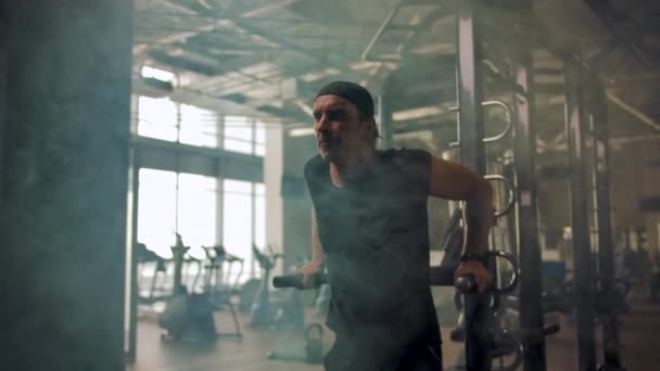 Un atleta maduro en un pañuelo está haciendo ejercicios en los bares irregulares en un gimnasio — Vídeos de Stock