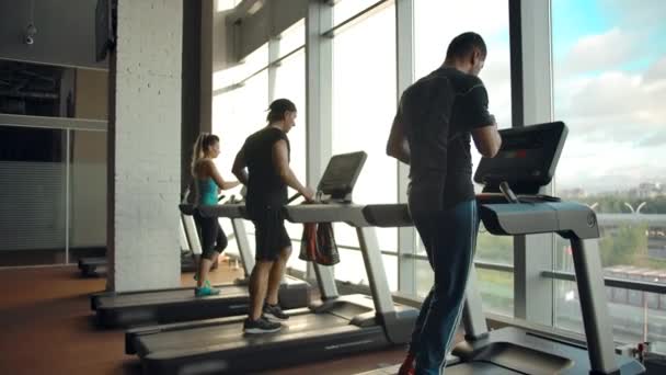 Modern spor salonunun içinde koşu bandında koşan sporcuların arka planı — Stok video