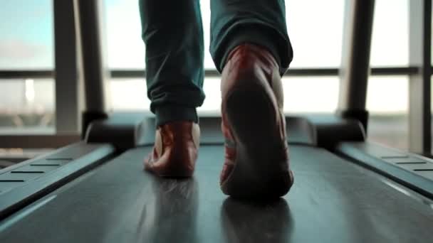 Vista trasera del hombre en zapatillas de deporte caminando en una cinta de correr — Vídeos de Stock