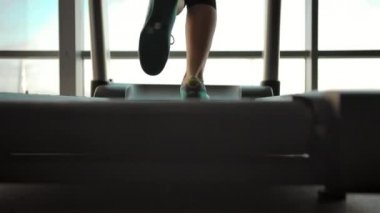 Koşu bandında koşan güzel bir kızın dikey manzarası.