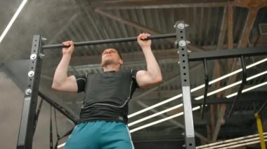 Erkek sporcu spor salonunun yatay çubuğuna yanaştı.