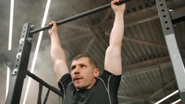 Spor salonunun yatay çubuğunda duran güçlü bir sporcunun portresi