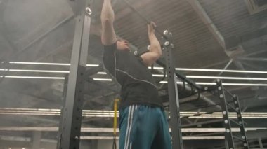 Beyaz tenli genç bir sporcu, spor salonunda dumanlı ve modern ışıklandırmalı kaldırma yapıyor.