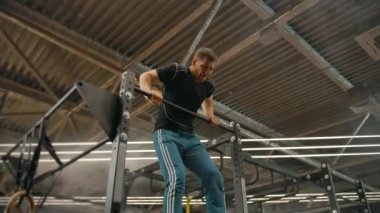 Güçlü bir erkek sporcu, spor salonundaki yatay bir barda güç kullanarak çıkış yolu bulur.