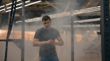 Spor salonundaki dumanda yürüyen bir sporcunun portresi.