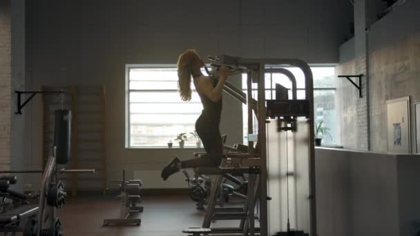 Широкий снимок красивой сексуальной девушки, делающей подтягивания на гравитроне — стоковое видео