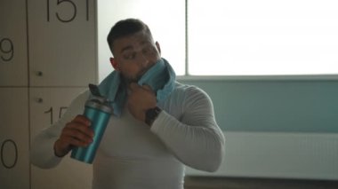 Spor yaptıktan sonra soyunma odasında dinlenen güçlü kaslı bir adamın portresi.