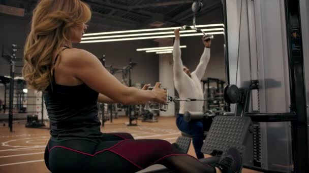 Couple in good physical shape are doing exercises on a exercise machine — Stock Video