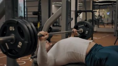 Güçlü erkek ağırlık kaldırırken halterle bankta yatıyor.