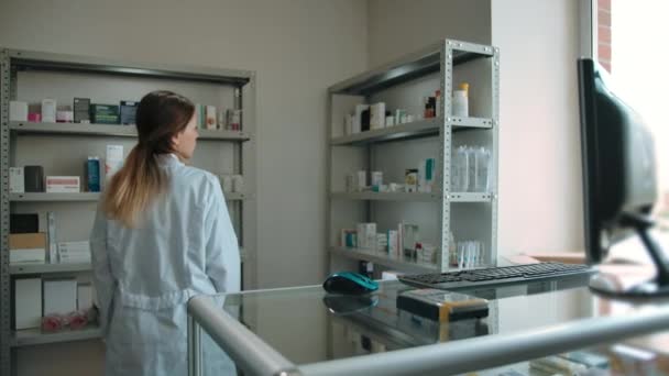 Dolly en tiro en la chica farmacéutica en el interior de la farmacia. — Vídeo de stock