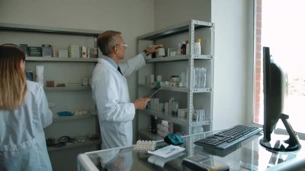 Два коллеги-фармацевта проверяют лекарства в аптеке — стоковое видео