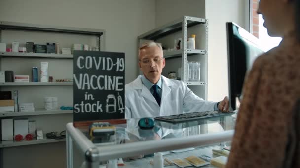 Covid-19 Impfstoff im Apothekenbestand. Apotheker bietet Kunden Impfstoff an. — Stockvideo