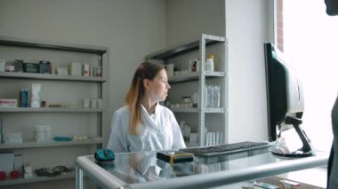 Müşteri eczanedeki kadın eczacıdan beyaz paketle sipariş alıyor.