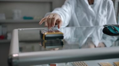 Bir adam eczanedeki siparişin parasını terminaldeki kredi kartıyla ödüyor..