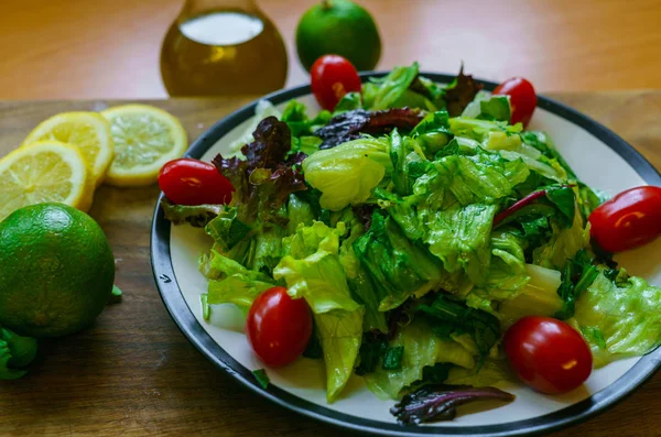 Świeże sałatki z różnych rodzajów zieleni i pomidorów wiśniowych, przyprawione oliwą z oliwek i sok z limonki z cytryną. — Zdjęcie stockowe