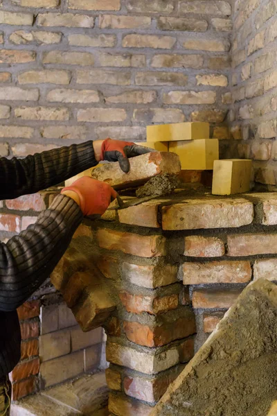 The builder lays down the bricks for the fireplace and fastens them with cement mortar.
