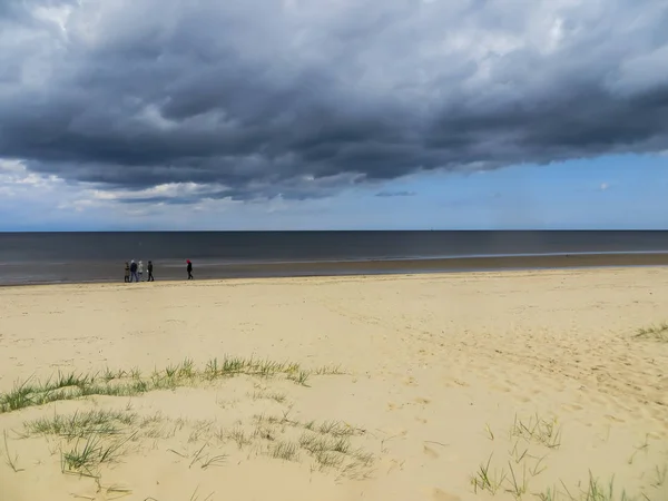 雷雨を見越して、早春にリガ湾の海岸に観光客のグループ. — ストック写真