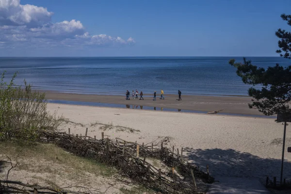 Hermosa vista del Golfo de Riga a principios de primavera. El mar está calmado.Un grupo de personas caminando por la orilla . — Foto de Stock