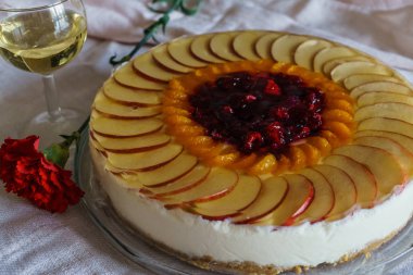 Elma, mandalina ve ahududu dilimleri ile dekore edilmiş ev yapımı süzme peynir kek.