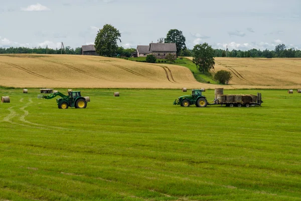 Un tracteur charge des balles de foin sur une remorque d'un autre tracteur . — Photo