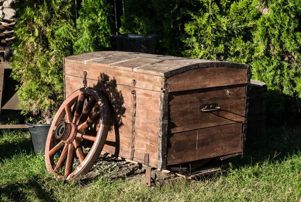 Old wooden chest and wooden cartwheel. Old things from the barn — Stock Photo, Image