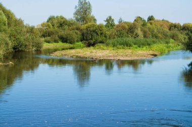 Yeşillikler ile çevrili nehrin manzarası, suya yansıdı.