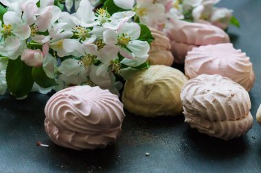 Lezzetli beyaz-pembe şekerlemeler ve bir elma ağacının çiçek açan dalı.