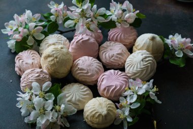 Lezzetli beyaz-pembe şekerlemeler ve bir elma ağacının çiçek açan dalı.