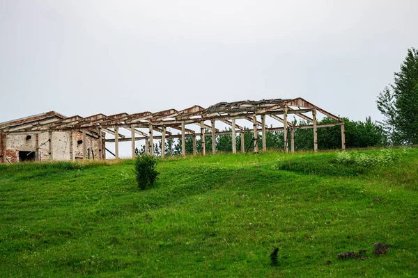 Restos abandonados de un granero roto en un campo en Letonia en verano. —  Fotos de Stock