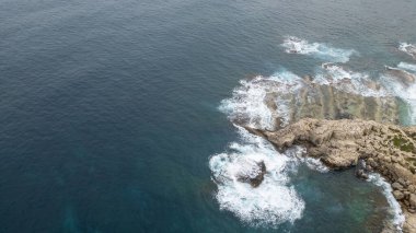 Dalgaların kayalarla buluştuğu yer Sicilya 'nın vahşi kıyı şeridi, engebeli sahili şekillendiren turkuaz deniz.