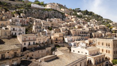 Güneşli bir barok kasabası olan Sicilya 'dan Modika tepelerden aşağı çağlayan altın evleri ve ebedi Akdeniz cazibesiyle.