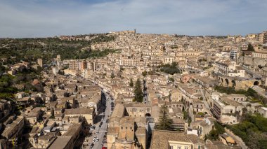 Güneşli bir barok kasabası olan Sicilya 'dan Modika tepelerden aşağı çağlayan altın evleri ve ebedi Akdeniz cazibesiyle.
