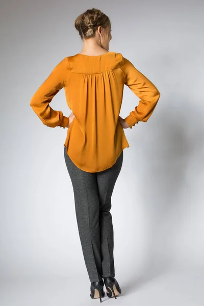 Young model posing in yellow blouse and gray pants