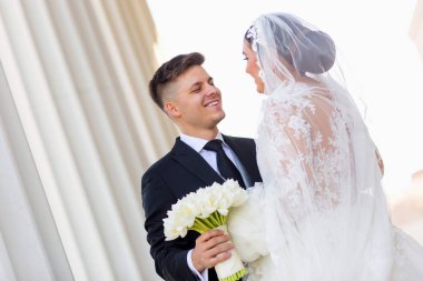 Güzel düğün çift sütun poz. Gelin holding buket çiçek