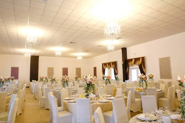 Beautiful white round table at the restaurant. Wedding reception day. Champagne and floral composition