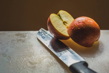 Bir yarım kesilmiş kırmızı büyük elma bir bıçak ile kesme tahtası. Büyük elma, çiğ gıda, vegans iki yarısı. Taze gıda, meyve.