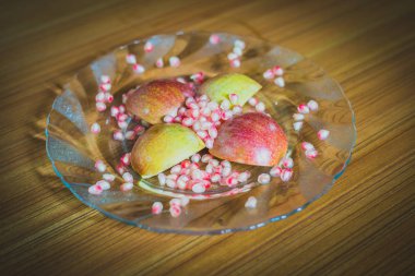 Taze elma dilim ve nar taneleri bir plaka üzerinde.