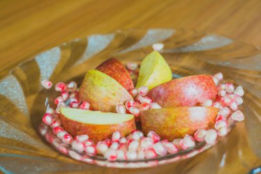 Taze elma dilim ve nar taneleri bir plaka üzerinde.