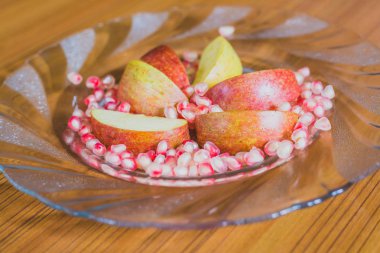 Taze elma dilim ve nar taneleri bir plaka üzerinde.