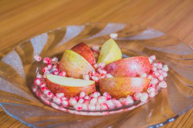 Taze elma dilim ve nar taneleri bir plaka üzerinde.