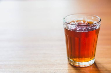 Cam çay bardağı ahşap masa üzerinde siyah masala çay.