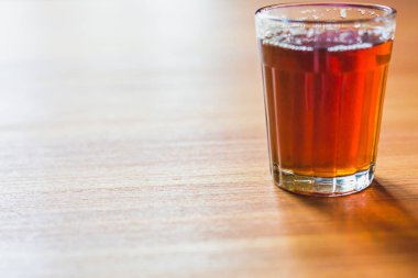 Cam çay bardağı ahşap masa üzerinde siyah masala çay.