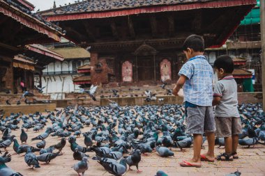 Kathmandu,Nepal - Jul 22,2018:Children  feeding pigeons at kathmandu Durbar Square in Kathmandu, Nepal clipart