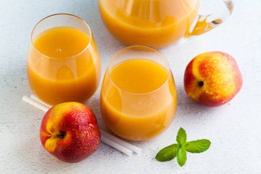 Şeftali suyu gözlük ve bir sürahi ve yaprakları bir tablo ile taze şeftali. mavi arka plan. kopya alanı