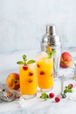 Şeftali suyu ve ahududu mermer bir tablo bir shaker ve aksesuarları bar uzun bardaklarda taze nane ile iki serinletici içecekler.