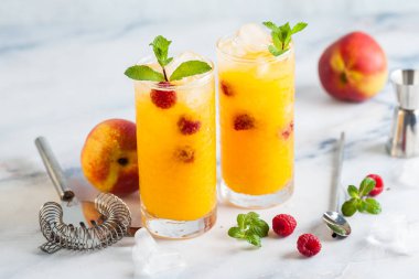 Şeftali suyu ve ahududu mermer bir tablo bir shaker ve aksesuarları bar uzun bardaklarda taze nane ile iki serinletici içecekler.